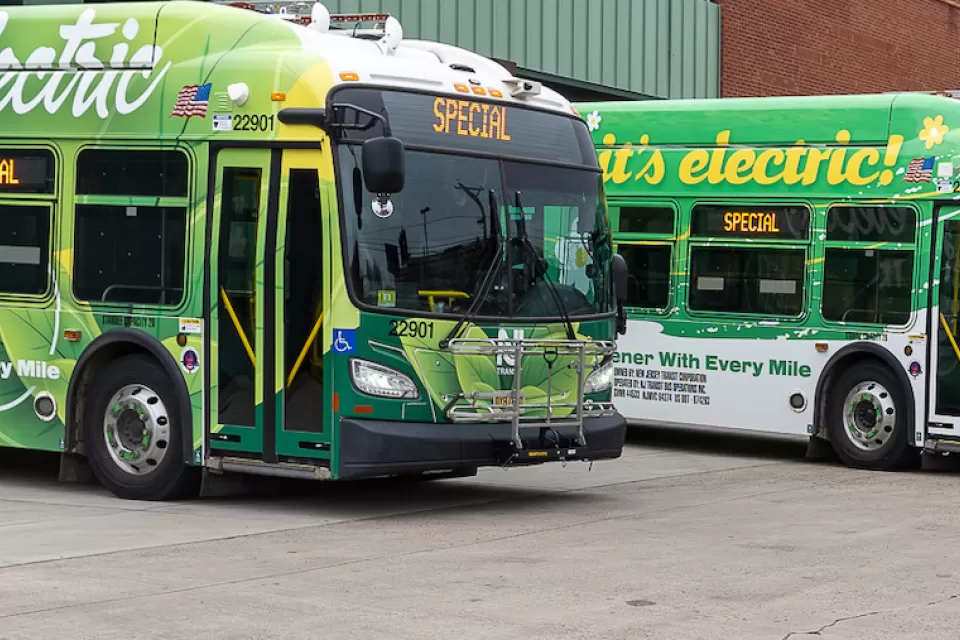 Parked green electric NJ Transit buses.